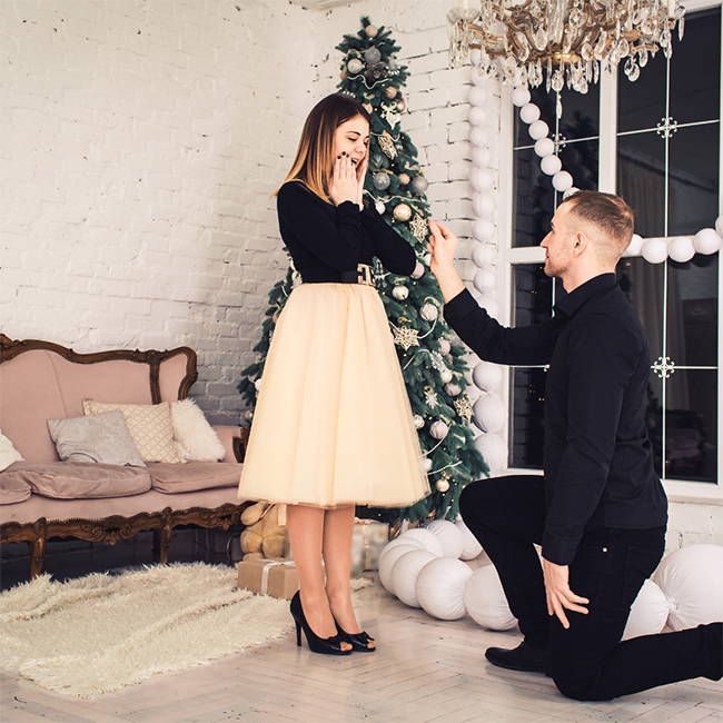 Proposta di matrimonio a Natale. Il fidanzato consegna l'anello. Marriage proposal at Christmas. The fiancé hands over the ring.
